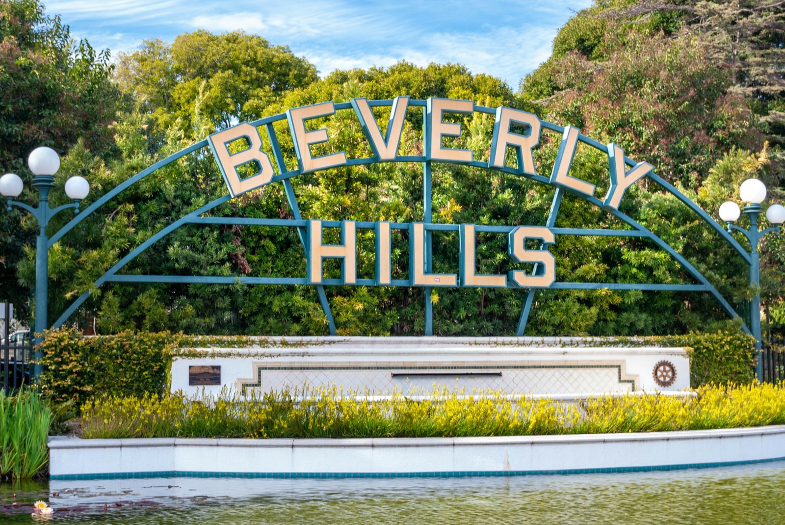 Beverly Hills sign framed by gardens and a reflecting lily pond
